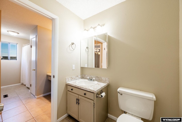 bathroom with tile patterned floors, toilet, a textured ceiling, baseboards, and vanity