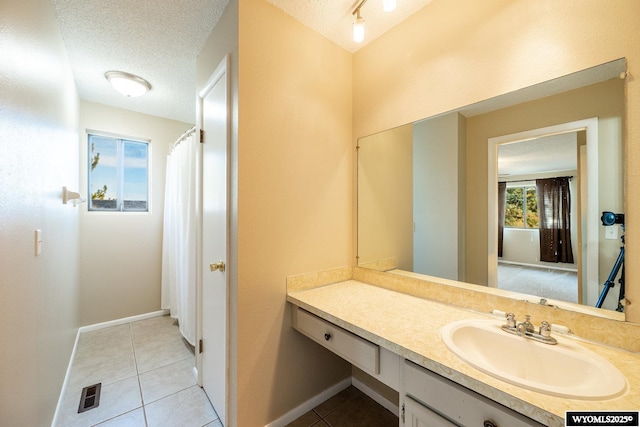 bathroom featuring tile patterned floors, visible vents, a textured ceiling, baseboards, and vanity