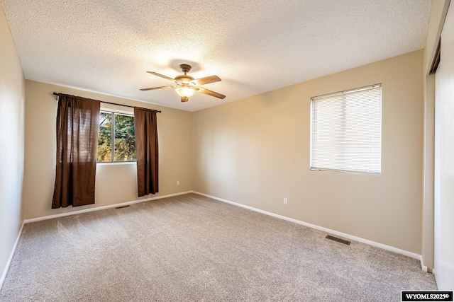 unfurnished room featuring baseboards, carpet, visible vents, and ceiling fan