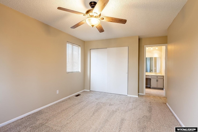 unfurnished bedroom with a ceiling fan, baseboards, a closet, a textured ceiling, and light carpet