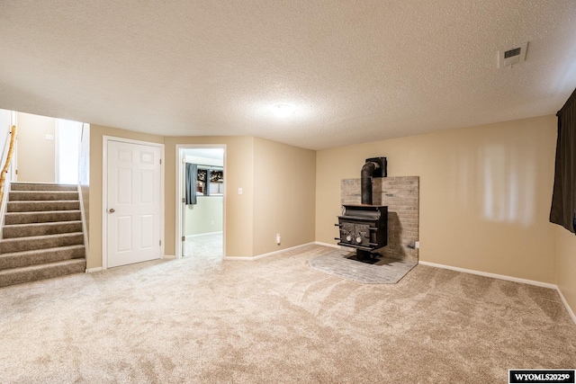 unfurnished living room with stairway, carpet flooring, and a wood stove