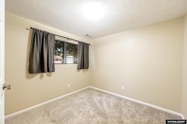 carpeted spare room featuring visible vents, baseboards, and a textured ceiling