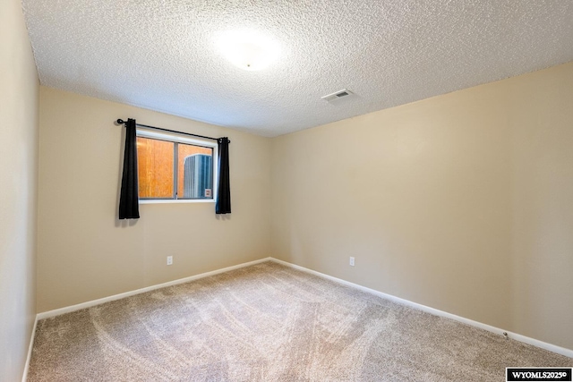 unfurnished room with visible vents, baseboards, a textured ceiling, and carpet flooring