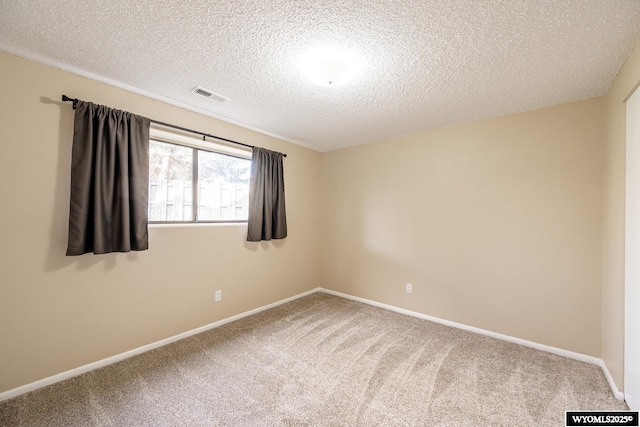 carpeted empty room with baseboards, visible vents, and a textured ceiling