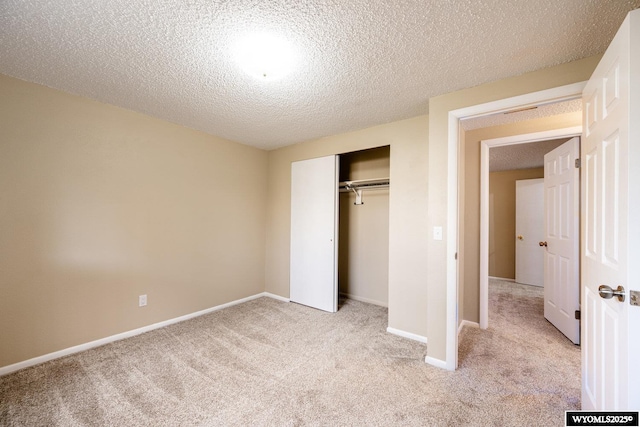 unfurnished bedroom featuring a closet, baseboards, light colored carpet, and a textured ceiling