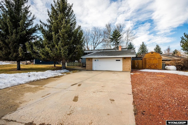 exterior space featuring a chimney, concrete driveway, an outdoor structure, and fence