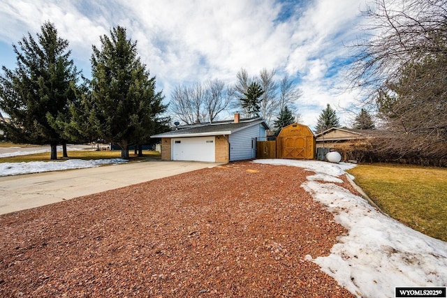 exterior space featuring brick siding, concrete driveway, a chimney, an attached garage, and a gate