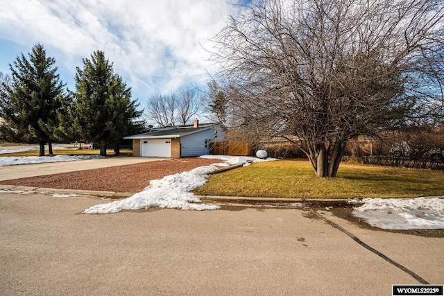 view of front of property with an attached garage, a chimney, driveway, and a front lawn