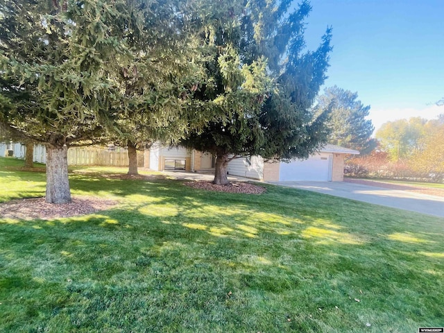 view of front of property featuring a front yard, an attached garage, fence, and concrete driveway