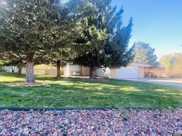 view of front of home featuring a front lawn, concrete driveway, a garage, and fence