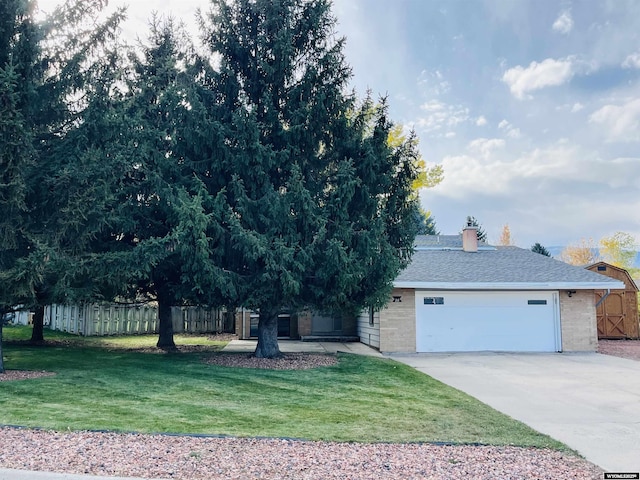 view of front facade with brick siding, fence, a front yard, a garage, and driveway