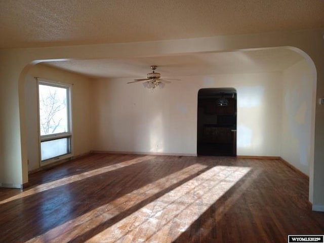1711 Elk Ave, Casper, WY 82601 - spare room featuring a textured ceiling, wood finished floors, arched walkways, baseboards, and ceiling fan