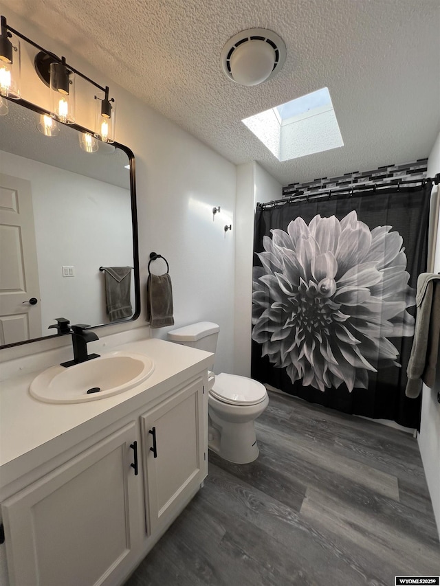 42 Carothers Ave, Fort Bridger, WY 82933 - bathroom with a textured ceiling, vanity, toilet, a skylight, and wood finished floors
