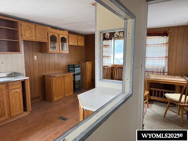 kitchen featuring visible vents, brown cabinets, wood walls, and light wood finished floors