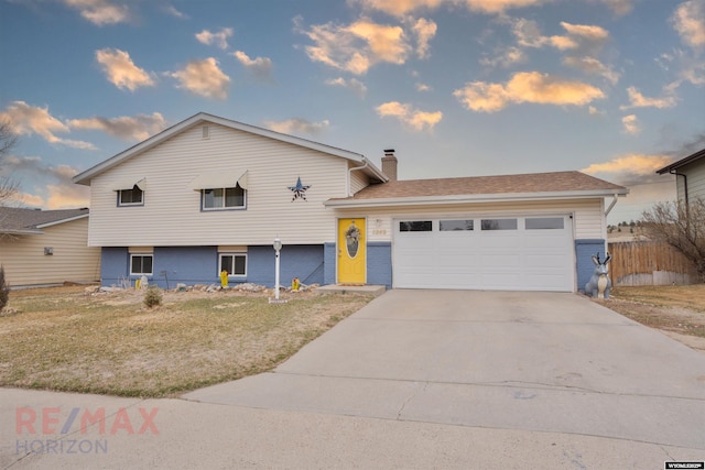 1242 Frontier Dr, Douglas, WY 82633 - tri-level home with a front lawn, concrete driveway, an attached garage, brick siding, and a chimney