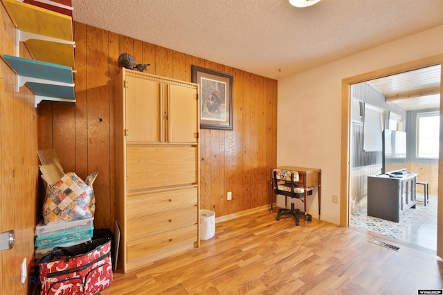 1242 Frontier Dr, Douglas, WY 82633 - interior space with light wood-type flooring, visible vents, a textured ceiling, wooden walls, and baseboards