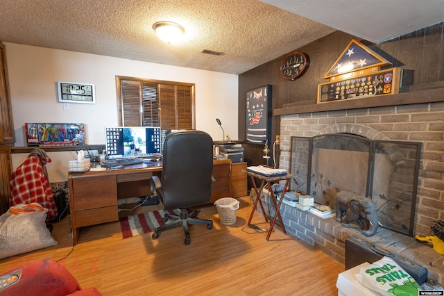 1242 Frontier Dr, Douglas, WY 82633 - home office with a brick fireplace, wood finished floors, visible vents, and a textured ceiling