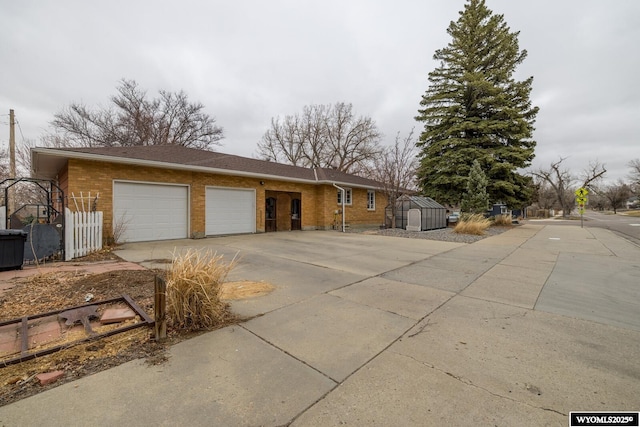 ranch-style house with a garage, brick siding, concrete driveway, and a shed