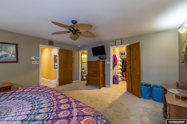bedroom featuring a walk in closet, a closet, carpet flooring, baseboards, and ceiling fan