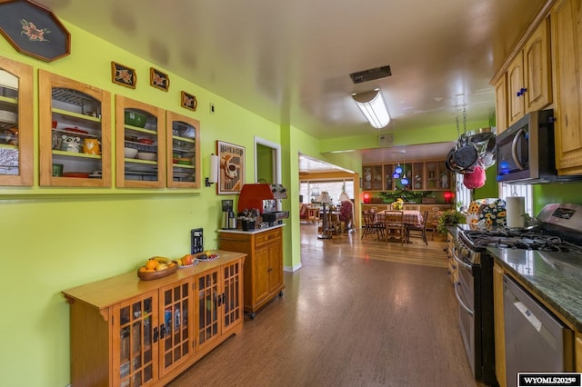 kitchen featuring dark wood-type flooring, glass insert cabinets, and appliances with stainless steel finishes