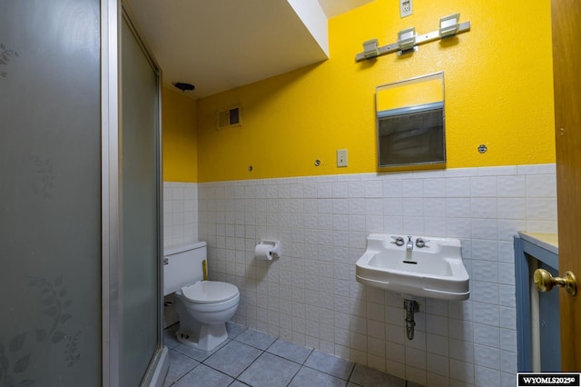 bathroom featuring tile patterned flooring, visible vents, a wainscoted wall, toilet, and a stall shower