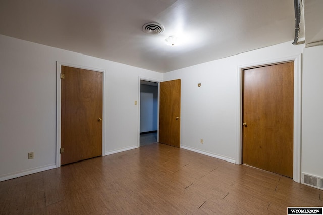 unfurnished bedroom featuring visible vents, baseboards, and wood finished floors