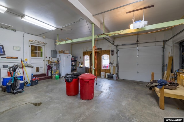 garage featuring a garage door opener and freestanding refrigerator
