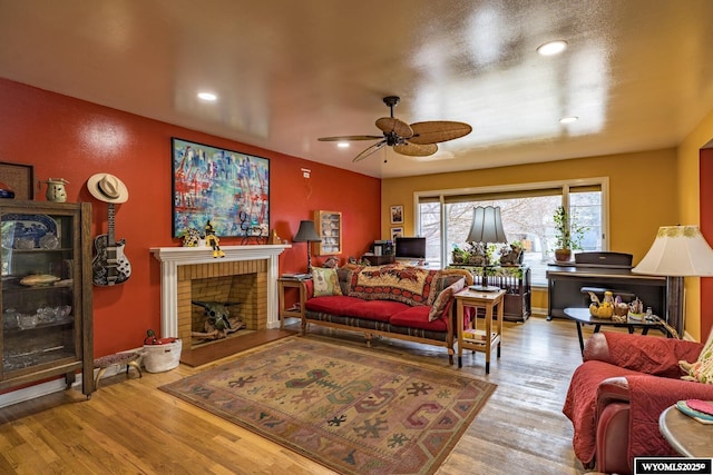 living room featuring ceiling fan, a brick fireplace, wood finished floors, and recessed lighting
