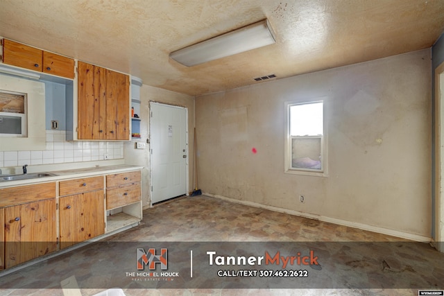 kitchen featuring visible vents, open shelves, a sink, backsplash, and light countertops