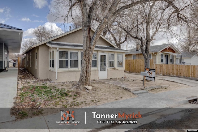 bungalow with stucco siding and fence