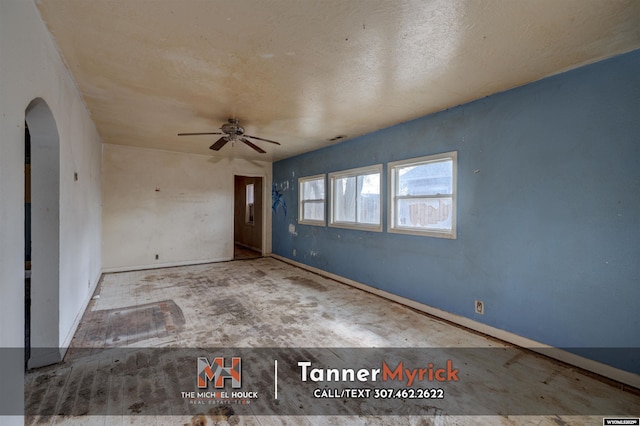 unfurnished room with arched walkways, baseboards, and a ceiling fan