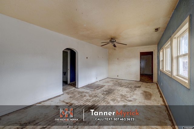 spare room featuring baseboards, visible vents, arched walkways, and ceiling fan