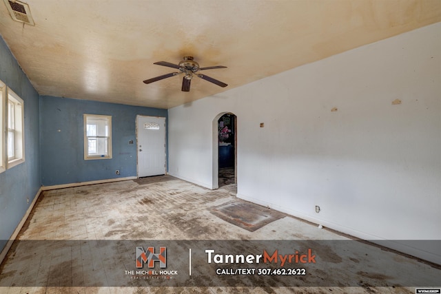 unfurnished room featuring visible vents, arched walkways, baseboards, and a ceiling fan