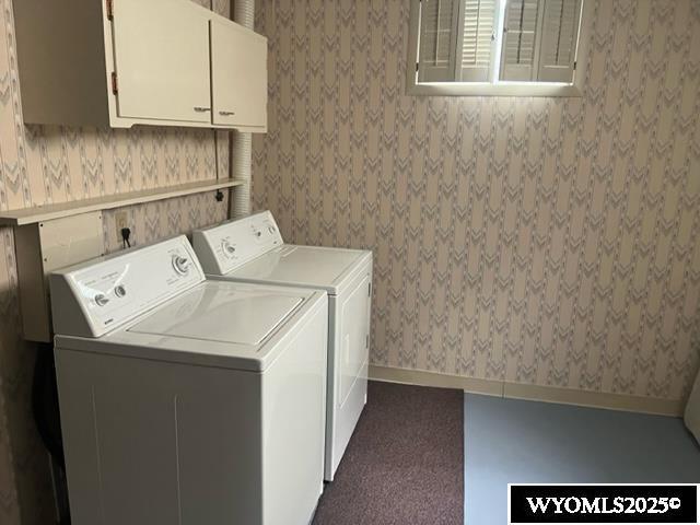 laundry area with separate washer and dryer, wallpapered walls, cabinet space, and baseboards