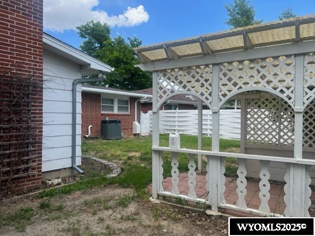 view of yard featuring central AC and fence