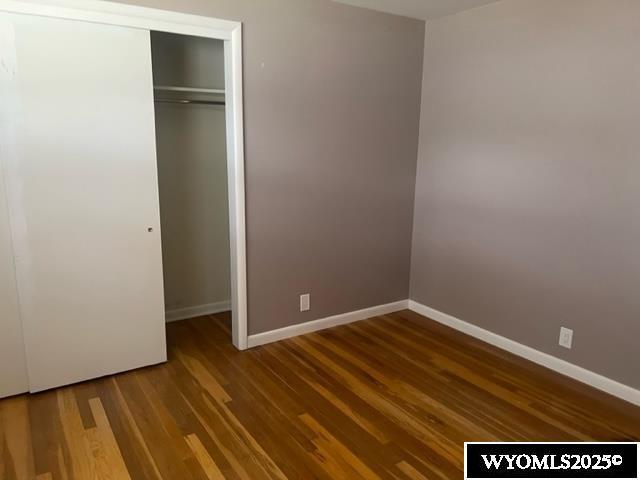 unfurnished bedroom with baseboards, a closet, and wood finished floors