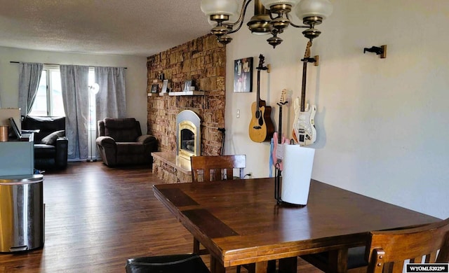 dining area with a fireplace, wood finished floors, a chandelier, and a textured ceiling