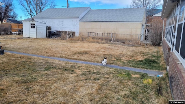 view of yard with a storage unit, an outbuilding, and fence