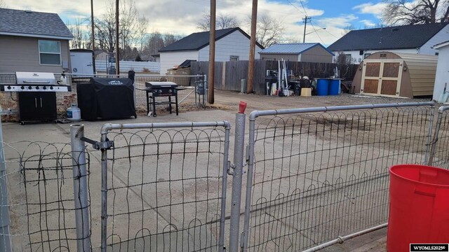 view of yard with a gate, a fenced front yard, an outbuilding, and a shed