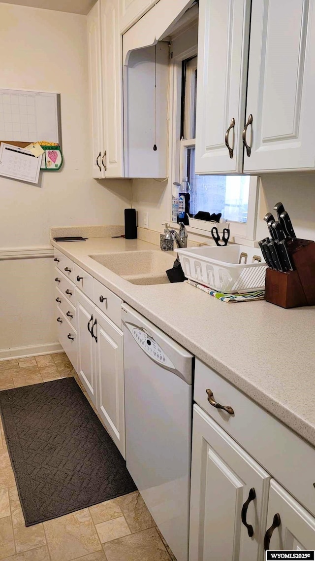kitchen featuring dishwasher, light countertops, white cabinetry, and a sink