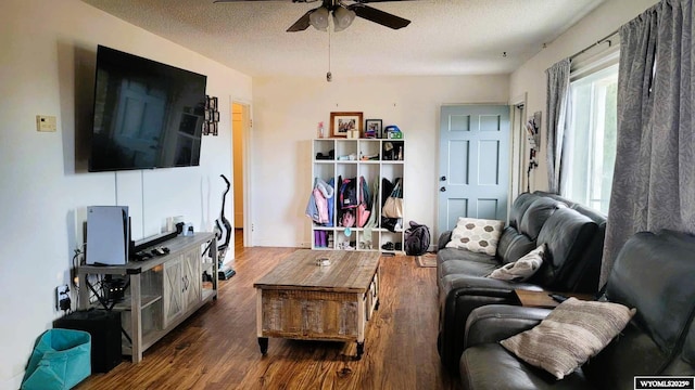living room featuring baseboards, a textured ceiling, ceiling fan, and wood finished floors