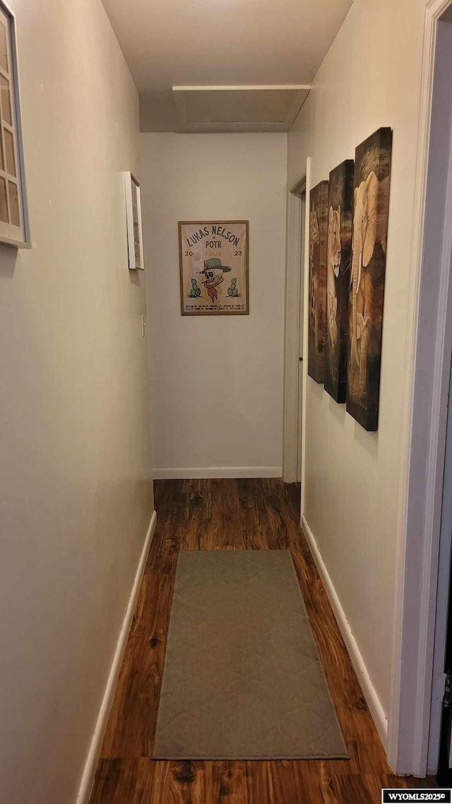 hallway with attic access, baseboards, and wood finished floors