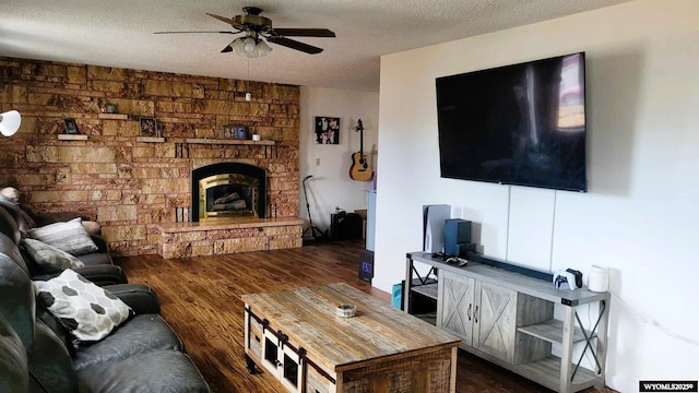 living area featuring a textured ceiling, a stone fireplace, wood finished floors, and ceiling fan