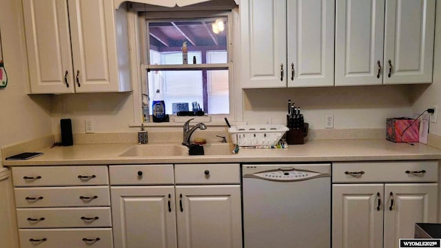 kitchen featuring white cabinets, dishwasher, light countertops, and a sink
