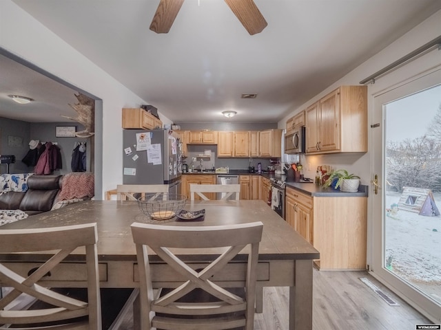 347 Copper, Evansville, WY 82636 - kitchen with light wood-style flooring, a ceiling fan, light brown cabinetry, dark countertops, and stainless steel appliances