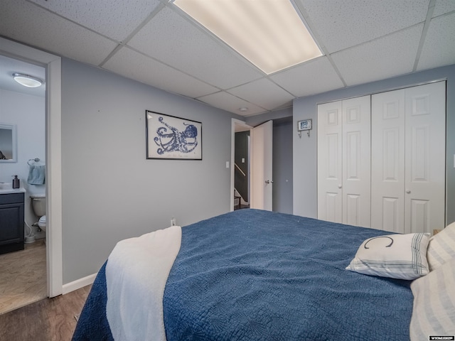 347 Copper, Evansville, WY 82636 - bedroom featuring wood finished floors, connected bathroom, a closet, baseboards, and a paneled ceiling
