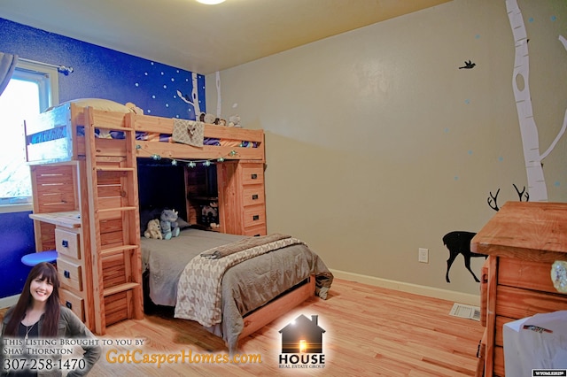 bedroom featuring baseboards, multiple windows, visible vents, and wood finished floors