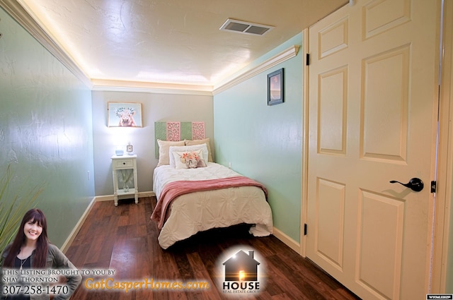 bedroom with baseboards, wood finished floors, visible vents, and ornamental molding