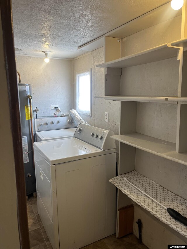 clothes washing area with water heater, washer and dryer, laundry area, and a textured ceiling