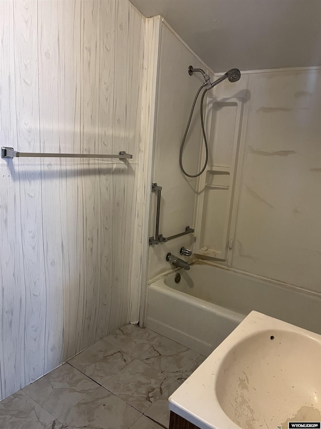 bathroom with marble finish floor, tub / shower combination, and a sink